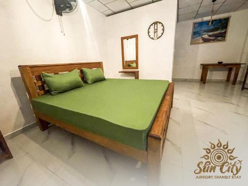 a bed with green sheets in a room at SunCity Airport Transit Stay in Minuwangoda