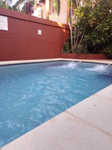 a swimming pool with blue water in front of a building at ARAMI HOTEL & LODGE in Puerto Iguazú