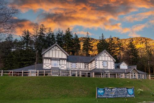 a large white house on a hill with trees at Plas Weunydd in Blaenau-Ffestiniog