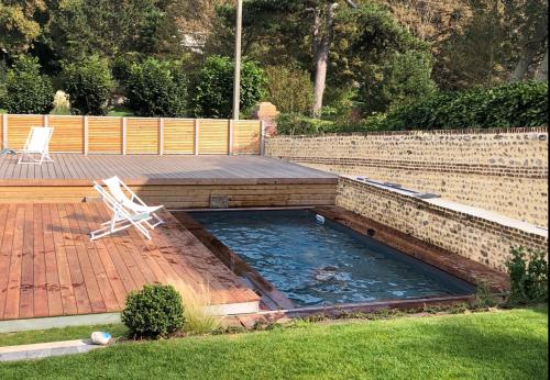 une piscine avec une chaise assise sur un patio dans l'établissement Maison familiale avec piscine Les Petites Dalles, à Sassetot-le-Mauconduit