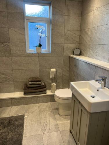 Un baño con inodoro, lavabo y ventana. en Chestnut House, en Southport