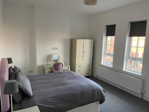 Un dormitorio con una cama y una cómoda y dos ventanas. en Chestnut House, en Southport