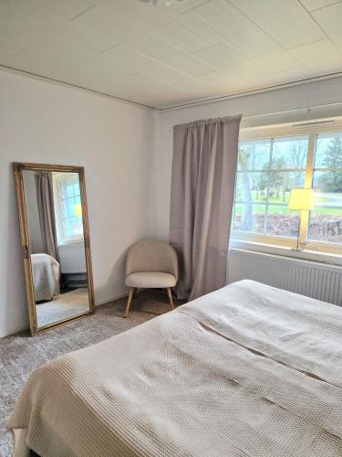 a bedroom with a bed and a mirror and a chair at Biskopskvarn in Skara
