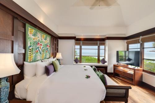 a bedroom with a large white bed and a flat screen tv at Napasai Samui in Mae Nam