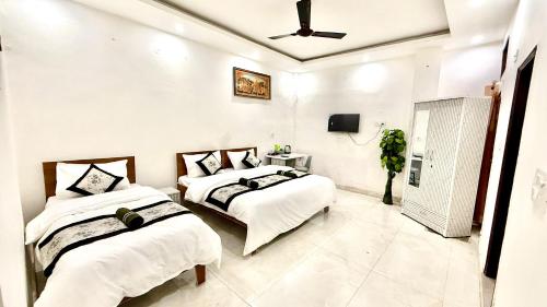 a bedroom with two beds and a tv on the wall at AB Residency in Greater Noida