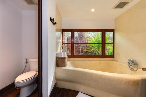 a bathroom with a tub and a toilet and a window at Napasai Samui in Mae Nam