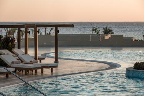 a pool with chairs and the ocean in the background at JAZ Elite Riviera in Marsa Alam City