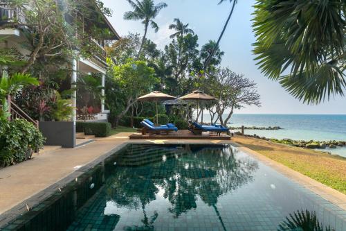 a swimming pool with two chairs and the ocean at Napasai Samui in Mae Nam