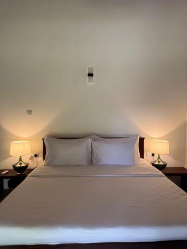 a bedroom with a white bed with two lamps at Maho Boutique Hotel in Anuradhapura