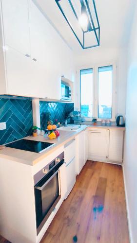 une cuisine avec des placards blancs et un comptoir bleu dans l'établissement Levalet BNB - La Défense Courbevoie, à Courbevoie