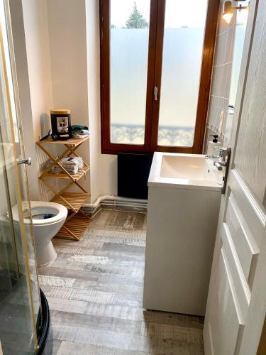 une salle de bain avec toilettes, lavabo et fenêtre dans l'établissement Bel appartement face à la gare, à Veneux-les-Sablons