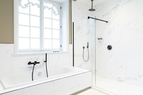 a white bathroom with a shower and a tub at Sapphire House Antwerp, Autograph Collection by Marriott in Antwerp