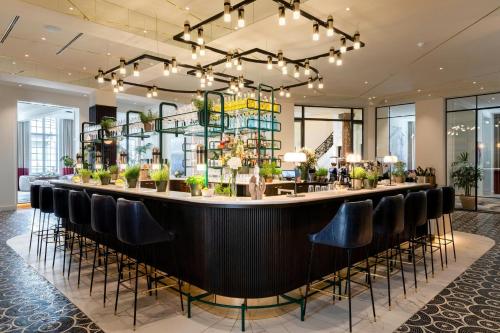 a bar in a hotel lobby with black chairs at Sapphire House Antwerp, Autograph Collection by Marriott in Antwerp