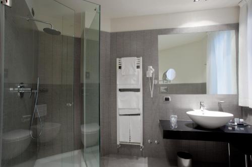 a bathroom with a sink and a glass shower at Hotel Ovest in Piacenza