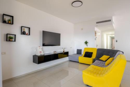 a living room with a yellow couch and a tv at Balfour sea view city center in Nahariyya