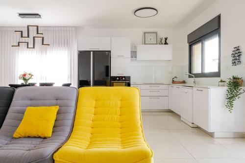 a living room with a yellow couch and a kitchen at Balfour sea view city center in Nahariyya