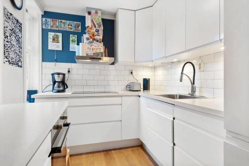 Una cocina blanca con gabinetes blancos y un fregadero. en Dinbnb Homes I Family Friendly Home in Historical Sandviken, en Bergen
