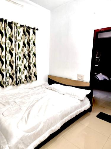 a bedroom with a bed with a black and white curtain at KP Home in Tellicherry