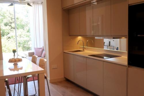 a kitchen with white cabinets and a table and a window at 1 bedroom modern en-suite apartment Nine Elms in London