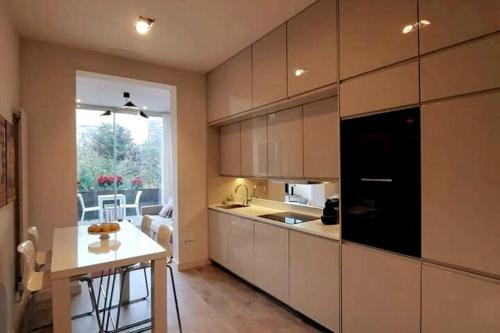 a kitchen with white cabinets and a table and a window at 1 bedroom modern en-suite apartment Nine Elms in London