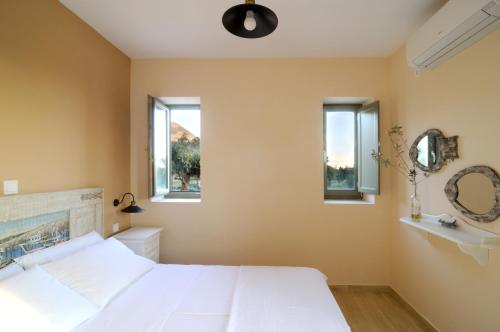 a bedroom with a white bed and two windows at Nikoloudi Estate in Agios Nikolaos