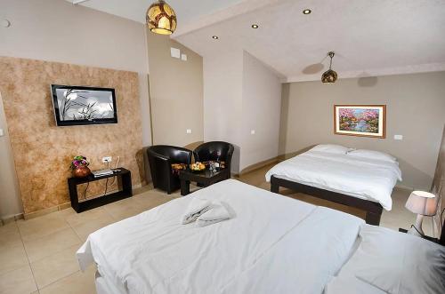 a hotel room with two beds and two chairs at אחוזת מצפה שני הימים-וילת 7 חדרים עם בריכה מחוממת וג'קוזי ספא in ‘Ein el Asad