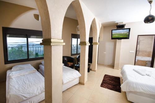 a bedroom with two beds and a flat screen tv at אחוזת מצפה שני הימים-וילת 7 חדרים עם בריכה מחוממת וג'קוזי ספא in ‘Ein el Asad