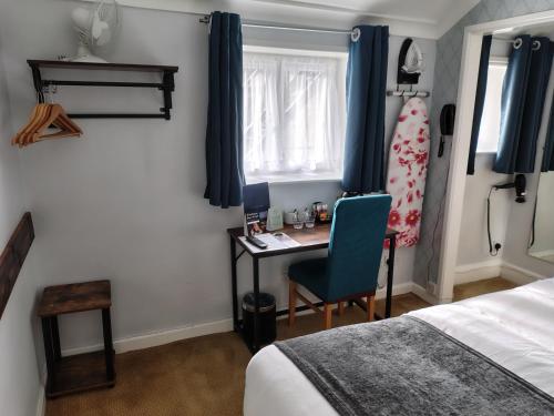 a bedroom with a bed and a desk with a blue chair at Rising Sun Hotel by Greene King Inns in Cheltenham