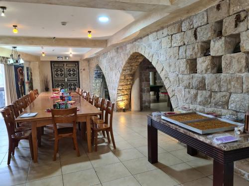 a dining room with a table and a stone wall at אחוזת מצפה שני הימים-וילת 7 חדרים עם בריכה מחוממת וג'קוזי ספא in ‘Ein el Asad