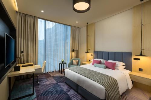 a bedroom with a bed and a desk and a television at Millennium Al Barsha in Dubai