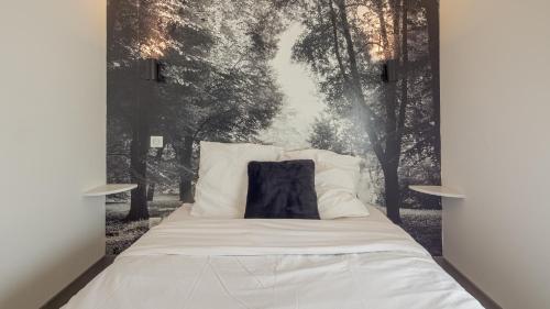 un lit avec une photo noire et blanche d'arbres dans l'établissement Les Suites du Jardin 4 - L'irrésistible - Hypercentre, à Chaumont