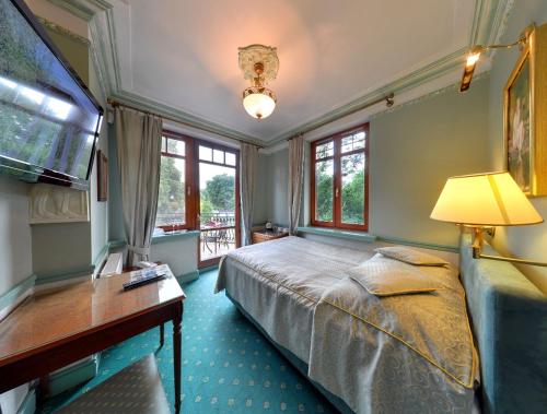 ein Schlafzimmer mit einem Bett, einem Schreibtisch und Fenstern in der Unterkunft Willa Amor in Krynica Morska