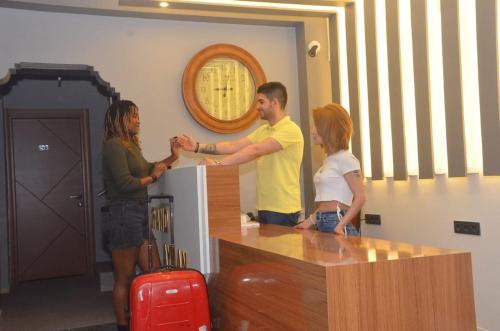 a man and woman standing at a counter with a girl at Grand Ayhan Hotel Kuşadası in Kusadası