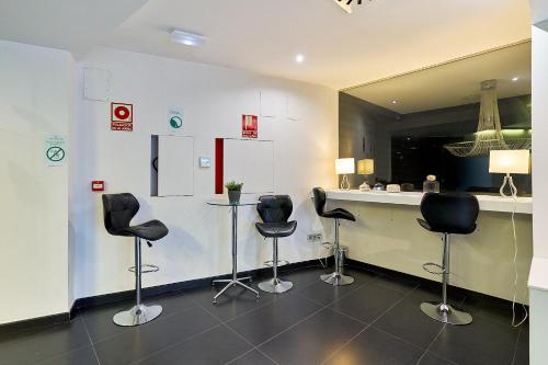 a barber shop with four black chairs and a counter at Hotel Barrio Húmedo by gaiarooms in León