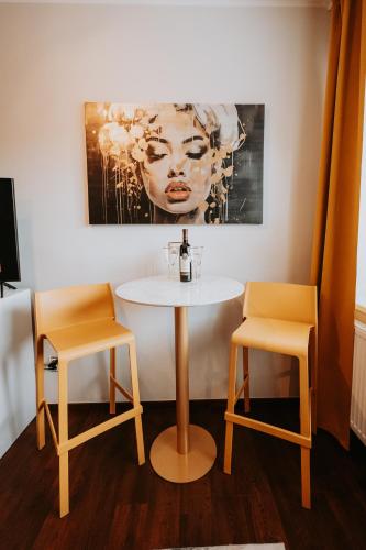a table and two chairs in a room with a painting at CityBeat Apartments, 400m from the square in Plzeň