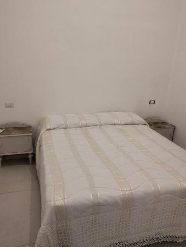 a bed in a white room with two tables at Orchidea in Matino