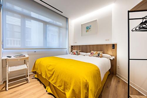 a bedroom with a yellow bed and a window at Apartamentos París Boutique Valladolid in Valladolid