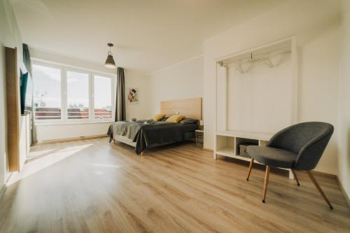 a bedroom with a bed and a chair and a window at CityBeat Apartments, 400m from the square in Plzeň