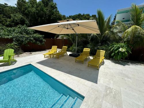a patio with chairs and an umbrella and a pool at Key Largo Home with Spa and Pool in Key Largo