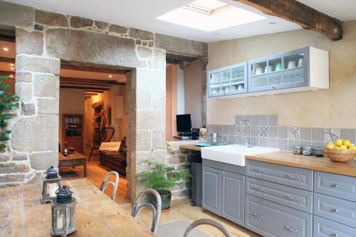 une cuisine avec des placards bleus et un mur en pierre dans l'établissement Town House In Quaint Breton Village, à Guéméné-sur-Scorff