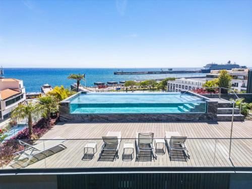 a view of a swimming pool with chairs and the ocean at Exclusive Terrace Apartment at Savoy Insular in Funchal