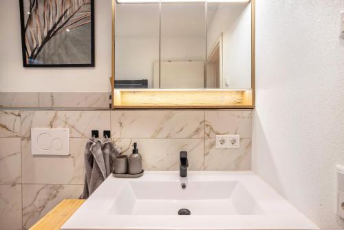 une salle de bain avec un lavabo blanc et un miroir dans l'établissement Ferienwohnung Alpenvorland, à Seeg