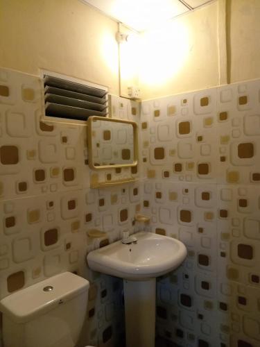 a bathroom with a toilet and a sink and a light at The Golden Bow in Seeduwa