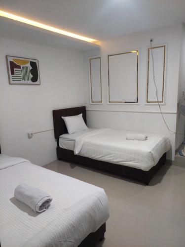 a room with two beds in a room with avertisement at Double D Guesthouse Syariah in Bukittinggi