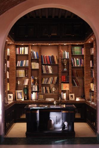 an archway in a room with a library with books at Jenan Mayshad Marrakech, Boutique hotel with Pool & Private Padel Court in Marrakech