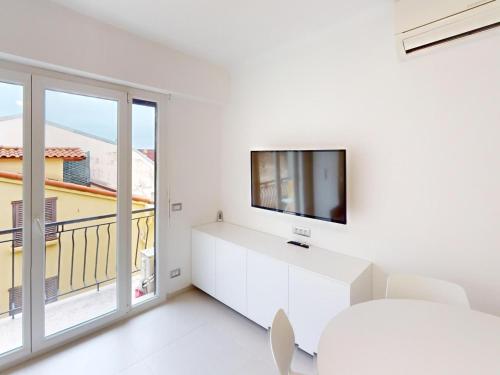 Il comprend un salon blanc doté d'une télévision et d'une fenêtre. dans l'établissement Studio moderne avec balcon, climatisation et WiFi - FR-1-196-214, à Menton