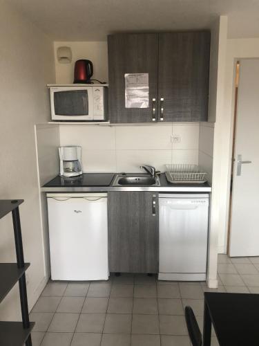 une petite cuisine avec un évier et un micro-ondes dans l'établissement A Gassin, résidence les jonquières 68, à Gassin