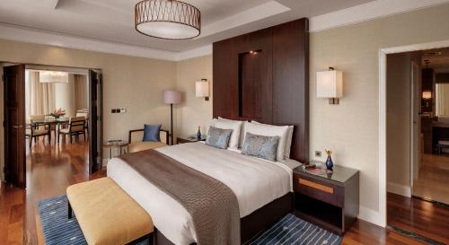 a hotel room with a large bed and a dining room at Kempinski Hotel Gold Coast City in Accra