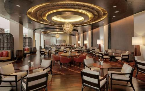 a restaurant with tables and chairs and a chandelier at Kempinski Hotel Gold Coast City in Accra