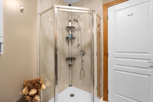 a shower with a glass door in a bathroom at Spacious 3-Story Golfside Townhouse with Pool Access Aiglon 1614 in Mont-Tremblant